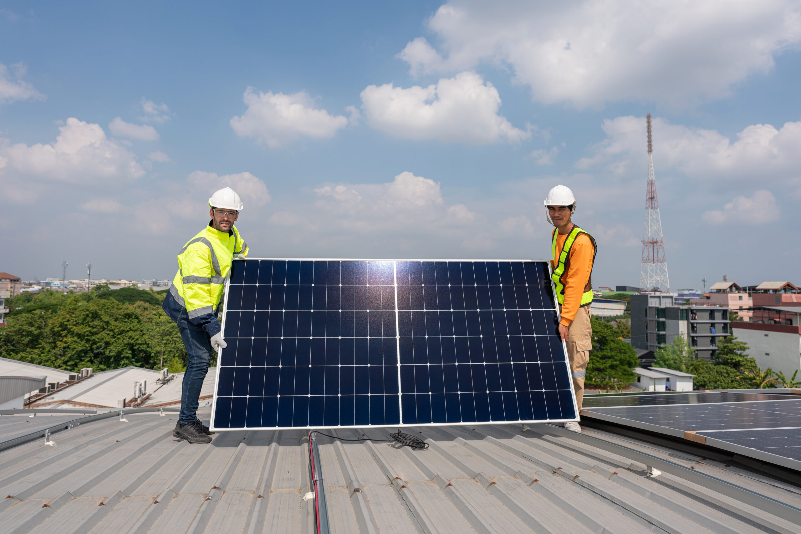 Men technicians carrying photovoltaic solar moduls on roof of factory on the morning. Installing a Solar Cell on a Roof. Solar panels on roof. Workers installing solar cell power plant eco technology.